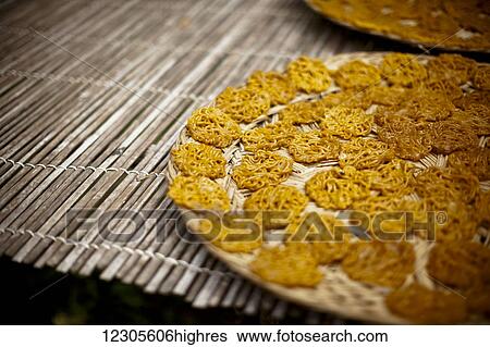 Stock Photograph - A locally made cracker called Krupuk, made from starch and other ingredients. Here the raw Krupuk are laid out to air dry, later they will be deep fried before eaten; Sumatra, Indonesia. Fotosearch