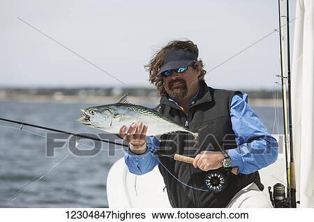 A man holds a fish on a fishing boat with a view of the coast; Cape Cod, Massachusetts, United States of America View Large Photo Image Stock Photograph - A man holds a fish on a fishing boat with a view of the coast; Cape Cod, Massachusetts, United States of America. Fotosearch