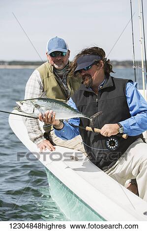 A man holds a fish on a fishing boat with a view of the coast; Cape Cod, Massachusetts, United States of America View Large Photo Image Stock Photograph - A man holds a fish on a fishing boat with a view of the coast; Cape Cod, Massachusetts, United States of America. Fotosearch