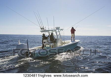 Stock Photograph - A man standing fishing off the edge of a boat on the Atlantic coast; Cape Cod, Massachusetts, United States of America. Fotosearch