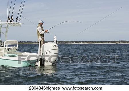 A man standing on the end of a fishing boat and fishing in the Atlantic Ocean off the coast of Cape Cod; Massachusetts, United States of America View Large Photo Image Stock Photograph - A man standing on the end of a fishing boat and fishing in the Atlantic Ocean off the coast of Cape Cod; Massachusetts, United States of America. Fotosearch