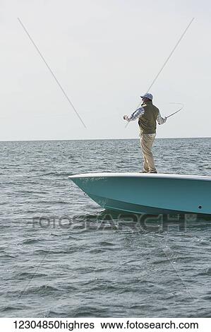 A man stands casting his fishing line off the front of a boat on the Atlantic coast; Cape Cod, Massachusetts, United States of America View Large Photo Image Stock Photograph - A man stands casting his fishing line off the front of a boat on the Atlantic coast; Cape Cod, Massachusetts, United States of America. Fotosearch