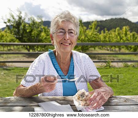 A mature woman eating ice-cream outside an ice-cream shop; Summerland, British Columbia, Canada View Large Photo Image Stock Photograph - A mature woman eating ice-cream outside an ice-cream shop; Summerland, British Columbia, Canada. Fotosearch