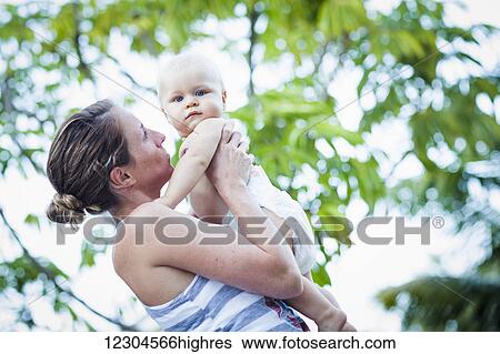 A mother holds her baby wearing only a diaper on a warm day; Fountain Valley, California, United States of America View Large Photo Image Stock Photograph - A mother holds her baby wearing only a diaper on a warm day; Fountain Valley, California, United States of America. Fotosearch