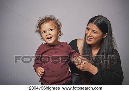 Stock Photograph - A mother with her young son on a grey background; Hamilton, Ontario, Canada. Fotosearch