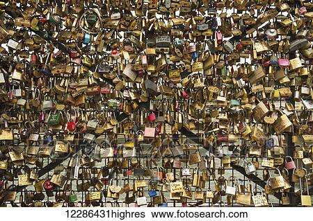 Stock Photograph - A multitude of padlocks tied to a bridge forming a pattern of shiny objects; Paris, France. Fotosearch