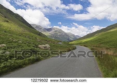 Stock Image - A paved road through the mountains; Cumbria, England. Fotosearch