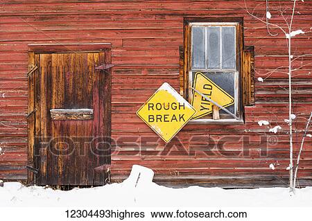 Stock Photograph - A red wooden building with two yellow signs, saying 'rough break' and 'yield'; Wetaskiwin, Alberta, Canada. Fotosearch