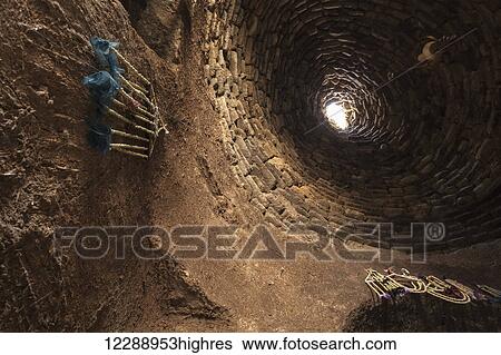 Stock Photograph - A round opening with sunlight viewed from an underground tunnel; Harran, Turkey. Fotosearch