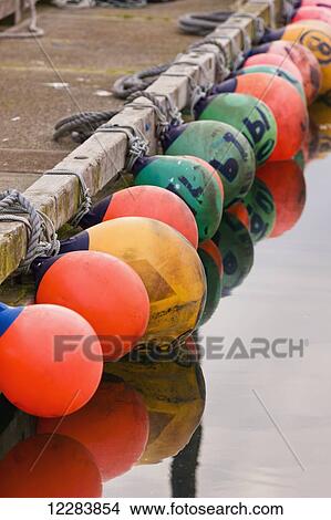 A row of multicolored buoys tied to a dock in Sand Point Harbor, Southwestern Alaska, USA, Summer View Large Photo Image Picture - A row of multicolored buoys tied to a dock in Sand Point Harbor, Southwestern Alaska, USA, Summer . Fotosearch