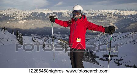Stock Photograph - A skier on a mountain top with a view of the Canadian Rocky mountains, Banff national park; Alberta, Canada. Fotosearch