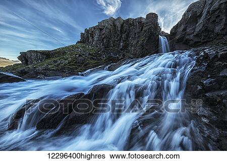 Stock Photograph - A small waterfall flows into the ocean along the eastern coast of Iceland; Iceland. Fotosearch