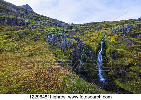 Stock Photograph - A small waterfall tumbles down the mountain side in one of Iceland eastern fjords; Iceland. Fotosearch