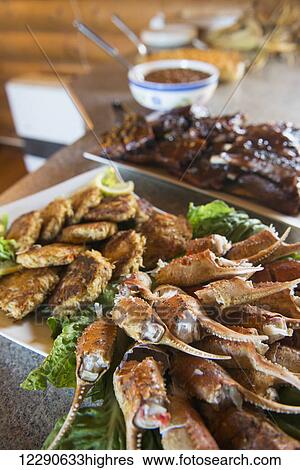 Stock Photograph - A spread of crab claws, crab cakes and barbecue ribs awaits guests at the Katmai Wilderness Lodge in Kukak Bay, Katmai National Park & Preserve, Alaska.. Fotosearch