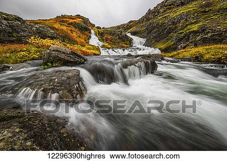 Stock Photograph - A stream flows past on the West Fjords on its way to the ocean; Iceland. Fotosearch
