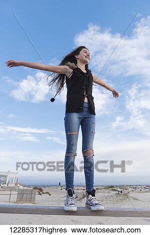 A teenage girl stands on the rail of a fence with arms outstretched; Tarifa, Cadiz, Andalusia, Spain View Large Photo Image Stock Photograph - A teenage girl stands on the rail of a fence with arms outstretched; Tarifa, Cadiz, Andalusia, Spain. Fotosearch
