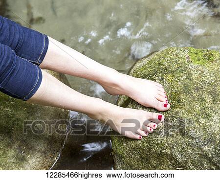 Stock Photograph - A teenage girl's bare feet with toenail polish on a moss covered rock; Chilliwack, British Columbia, Canada. Fotosearch