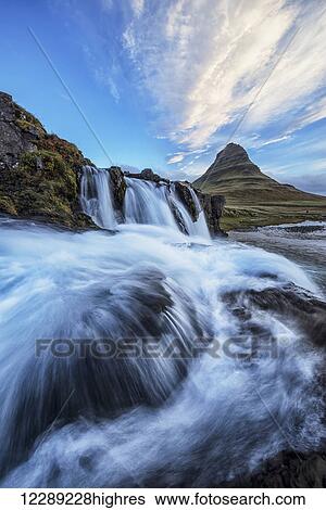 Stock Photograph - A waterfall flows in the foreground of Kirkjufell, the most iconic and photographed mountain in Iceland; Iceland. Fotosearch
