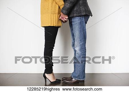 Stock Photograph - A woman and a man holding hands and standing close; Toronto, Ontario, Canada. Fotosearch