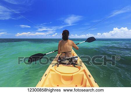 A woman in a bikini in a kayak on the Caribbean, Saint Georges Caye Resort; Belize City, Belize View Large Photo Image Stock Photograph - A woman in a bikini in a kayak on the Caribbean, Saint Georges Caye Resort; Belize City, Belize. Fotosearch