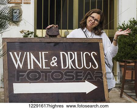 Stock Photograph - A woman posing with a sign for wine and drugs; Ravello, Italy. Fotosearch
