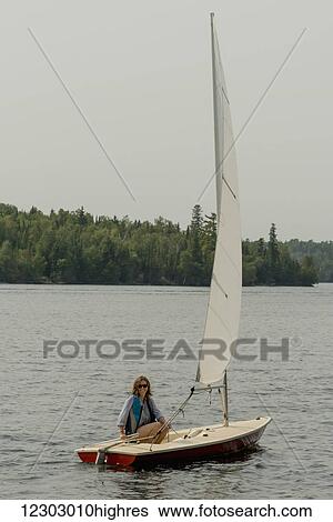 A woman sits on a small sailboat in a lake; Ontario, Canada View Large Photo Image Stock Photograph - A woman sits on a small sailboat in a lake; Ontario, Canada. Fotosearch