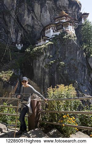 A woman stands at a railing with Taktsang Palphug Monastery in the background; Paro, Bhutan View Large Photo Image Stock Photograph - A woman stands at a railing with Taktsang Palphug Monastery in the background; Paro, Bhutan. Fotosearch