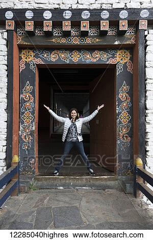 Stock Photograph - A woman stands in an ornate doorway, Rinpung Dzong; Paro, Bhutan. Fotosearch