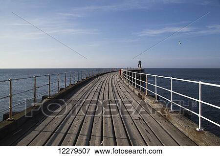 A wooden pier with white railing leading out to the water; Whitby, Yorkshire, England View Large Photo Image Stock Photo - A wooden pier with white railing leading out to the water; Whitby, Yorkshire, England. Fotosearch