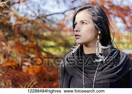 Stock Photograph - A young aboriginal female model headshot looking away in a thoughtful expression posed in the outdoors in autumn. Fotosearch