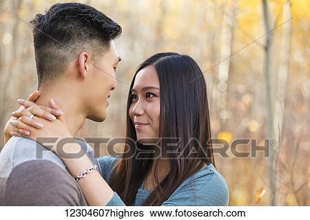 A young Asian couple enjoying a romantic time together outdoors in a park in autumn and embracing each other in the warmth of the sunlight; Edmonton, Alberta, Canada View Large Photo Image Stock Photograph - A young Asian couple enjoying a romantic time together outdoors in a park in autumn and embracing each other in the warmth of the sunlight; Edmonton, Alberta, Canada. Fotosearch