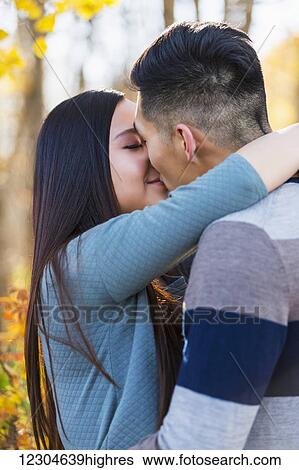 A young Asian couple enjoying a romantic time together outdoors in a park in autumn and embracing each other in the warmth of the sunlight during the early evening; Edmonton, Alberta, Canada View Large Photo Image Stock Photograph - A young Asian couple enjoying a romantic time together outdoors in a park in autumn and embracing each other in the warmth of the sunlight during the early evening; Edmonton, Alberta, Canada. Fotosearch