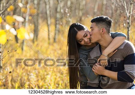 A young Asian couple enjoying quality time together outdoors in a park in autumn and embracing and kissing each other in the warmth of the sunlight; Edmonton, Alberta, Canada View Large Photo Image Stock Photograph - A young Asian couple enjoying quality time together outdoors in a park in autumn and embracing and kissing each other in the warmth of the sunlight; Edmonton, Alberta, Canada. Fotosearch