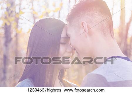 A young Asian couple enjoying quality time together outdoors in a park in autumn and touching their foreheads together affectionately in the warmth of the evening sun; Edmonton, Alberta, Canada View Large Photo Image Stock Photograph - A young Asian couple enjoying quality time together outdoors in a park in autumn and touching their foreheads together affectionately in the warmth of the evening sun; Edmonton, Alberta, Canada. Fotosearch