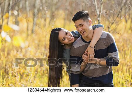 A young Asian couple enjoying quality time together outdoors in a park in autumn and embracing each other in the warmth of the sunlight during the early evening; Edmonton, Alberta, Canada View Large Photo Image Stock Photograph - A young Asian couple enjoying quality time together outdoors in a park in autumn and embracing each other in the warmth of the sunlight during the early evening; Edmonton, Alberta, Canada. Fotosearch