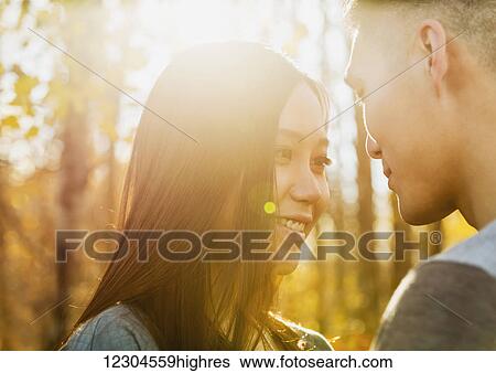 Stock Photograph - A young Asian couple enjoying quality time together in a park in autumn and enjoying the warmth of the evening sunshine; Edmonton, Alberta, Canada. Fotosearch