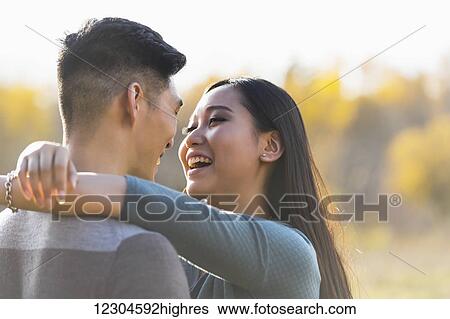 A young Asian couple enjoying quality time together outdoors in a park in autumn and embracing each other in the warmth of the sunlight during the early evening; Edmonton, Alberta, Canada View Large Photo Image Stock Photograph - A young Asian couple enjoying quality time together outdoors in a park in autumn and embracing each other in the warmth of the sunlight during the early evening; Edmonton, Alberta, Canada. Fotosearch