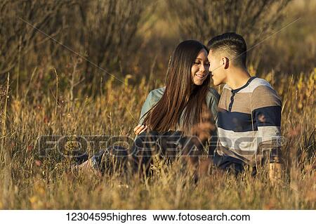 Stock Photograph - A young Asian couple enjoying quality time together outdoors in a park in autumn in the warmth of the sunlight during the early evening; Edmonton, Alberta, Canada. Fotosearch