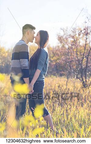 A Young Asian Couple Enjoying Quality Time Together Outdoors In A Park In Autumn And Holding Hands In The Warmth Of The Sunlight During The Early Evening Hours Edmonton Alberta Canada Stock