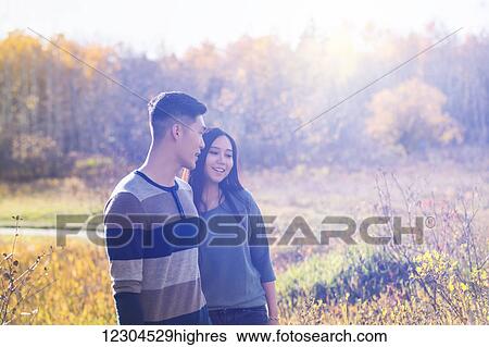 A young Asian couple holding hands while walking in a park in autumn and enjoying the warmth of the evening sunlight; Edmonton, Alberta, Canada View Large Photo Image Stock Photograph - A young Asian couple holding hands while walking in a park in autumn and enjoying the warmth of the evening sunlight; Edmonton, Alberta, Canada. Fotosearch