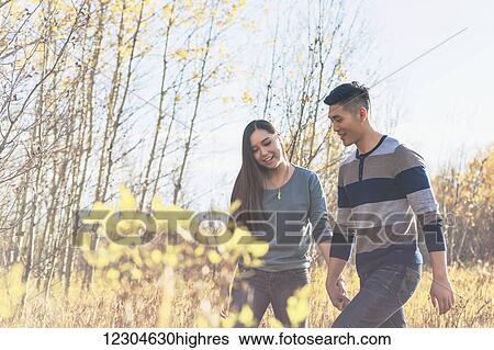 A young Asian couple holding hands while walking through a park in autumn and enjoying the warmth of the sunlight during the early evening; Edmonton, Alberta, Canada View Large Photo Image Stock Photograph - A young Asian couple holding hands while walking through a park in autumn and enjoying the warmth of the sunlight during the early evening; Edmonton, Alberta, Canada. Fotosearch