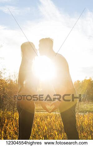 A young Asian couple kissing in a park in autumn and making a heart with their hands in the warmth of the setting sun; Edmonton, Alberta, Canada View Large Photo Image Stock Photograph - A young Asian couple kissing in a park in autumn and making a heart with their hands in the warmth of the setting sun; Edmonton, Alberta, Canada. Fotosearch