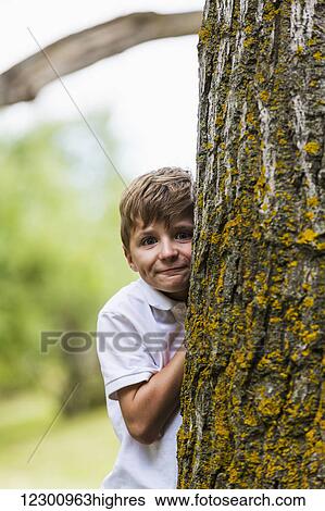 A young boy posing beside a tree trunk in a park; Edmonton, Alberta, Canada View Large Photo Image Stock Photograph - A young boy posing beside a tree trunk in a park; Edmonton, Alberta, Canada. Fotosearch