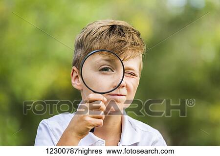 Stock Photograph - A young boy using a magnifying glass in a park; Edmonton, Alberta. Fotosearch