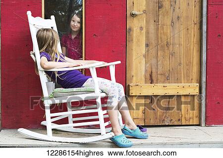 A young girl looks out a window at another girl sitting in a rocking chair on the porch; Salmon Arm, British Columbia, Canada View Large Photo Image Stock Photograph - A young girl looks out a window at another girl sitting in a rocking chair on the porch; Salmon Arm, British Columbia, Canada. Fotosearch