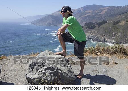 A young man stands on a ridge overlooking the ocean and California coastline; Big Sur, California, United States of America View Large Photo Image Stock Photograph - A young man stands on a ridge overlooking the ocean and California coastline; Big Sur, California, United States of America. Fotosearch