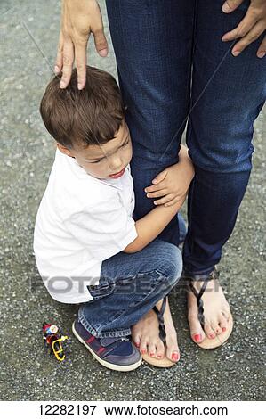 Stock Photo - A young son holding on to his mother's leg; Chilliwack, British Columbia, Canada. Fotosearch