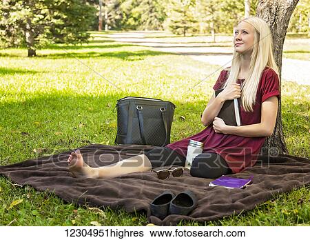 A young woman holding her Bible close to her chest while spending personal devotional time outdoors in a park in autumn; Edmonton, Alberta, Canada View Large Photo Image Stock Photograph - A young woman holding her Bible close to her chest while spending personal devotional time outdoors in a park in autumn; Edmonton, Alberta, Canada. Fotosearch