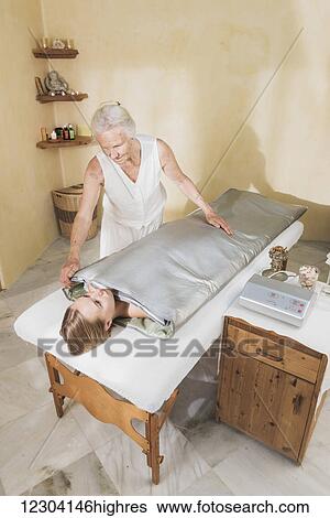 Stock Photograph - A young woman laying on a treatment table at a spa getting a treatment; Tarifa, Cadiz, Andalusia, Spain. Fotosearch