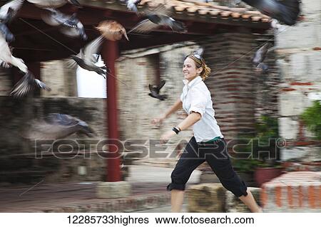 A young woman runs after a flock of birds taking flight; Cartagena, Columbia View Large Photo Image Stock Photograph - A young woman runs after a flock of birds taking flight; Cartagena, Columbia. Fotosearch